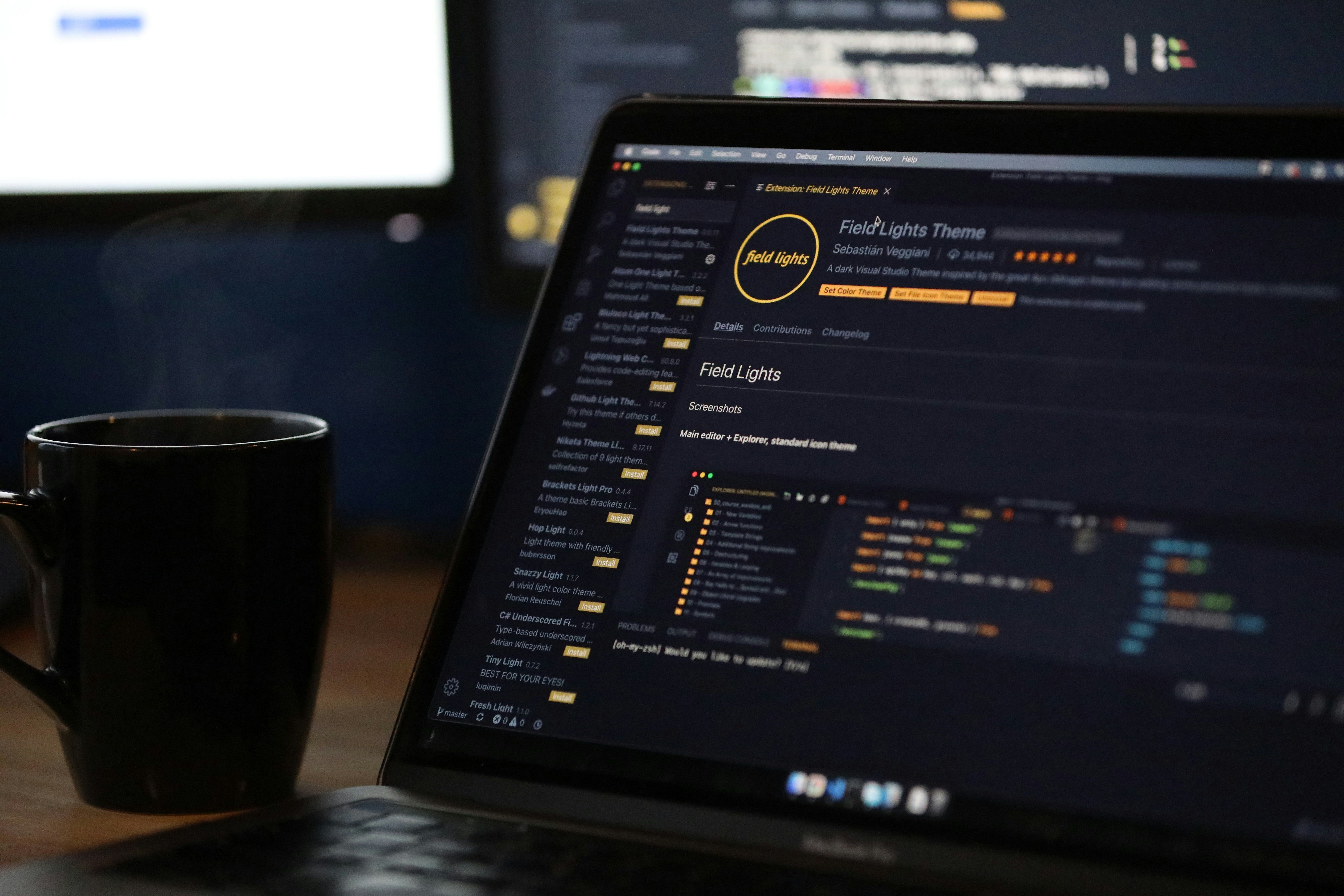 An image of a computer on a desk flanked by a warm cup of coffee